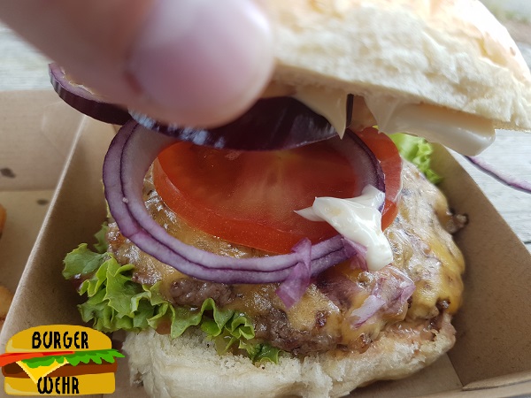 Ein aufgeklappter Cheeseburger mit verschiedenen Zutaten