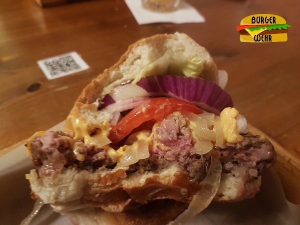 Angebissener Cheeseburger mit rosanem Fleisch im Zentrum