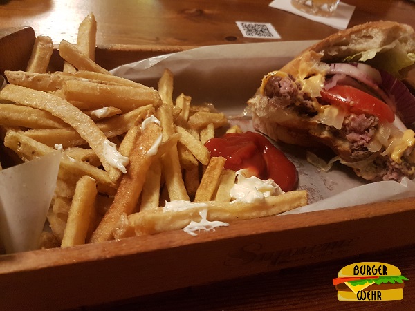 Ein großer Haufen Pommes Frittes neben einem Cheeseburger
